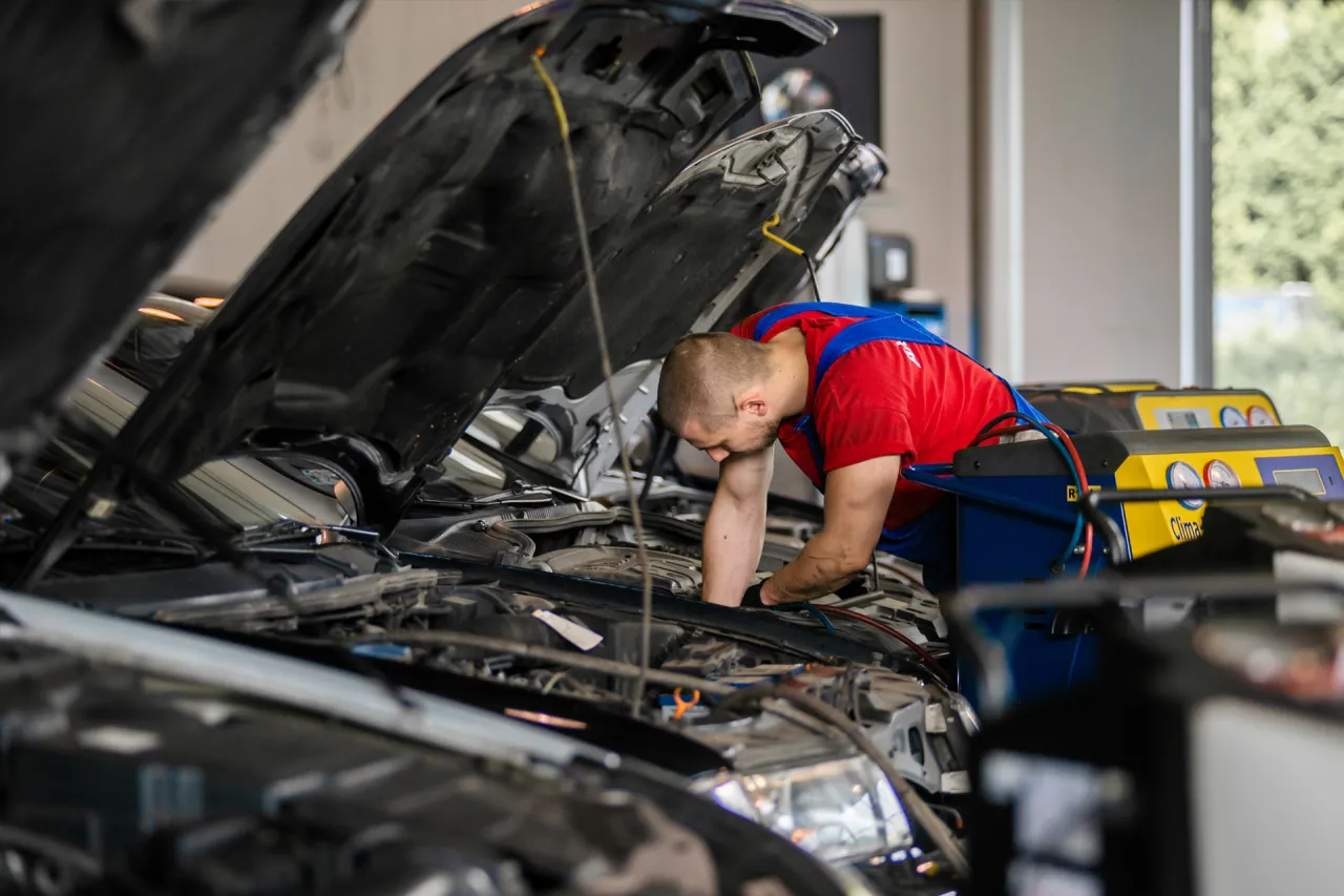 Mechanik MOTOER pracujący przy otwartej komorze silnika podczas obsługi klimatyzacji